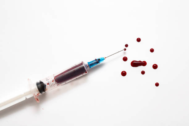 Closeup Of A Disposable Syringe And Many Blood Drops Isolated On White Close Up