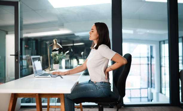 Shot Of A Young Businesswoman Experiencing Back Pain While Working In An Office
